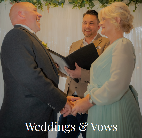 Photograph of Neil, celebrant for Leicestershire, conducting a wedding. He is in the middle of the picture wearing a cream suit and holding vows. In front of him are the bride and groom. The Groom is laughing. The bride is wearing a blue wedding dress. Click on the image will take you to the weddings and vows page of the website.